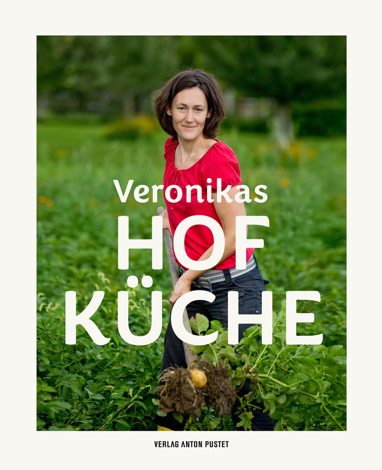Cover des Kochbuches Veronikas Hofküche, Veronika Brudl in rotem T-Shirt und blauer Jeans am Erdäpfelacker, bei der Arbeit mit Schaufel und Erdäpfel, Kartoffel 